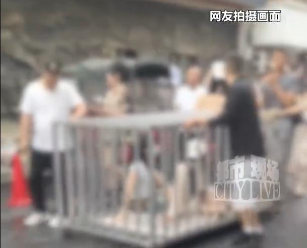 两女子与狗被关进钢笼游街，笼顶挂着偷人的牌子：摆拍低俗场景博流量